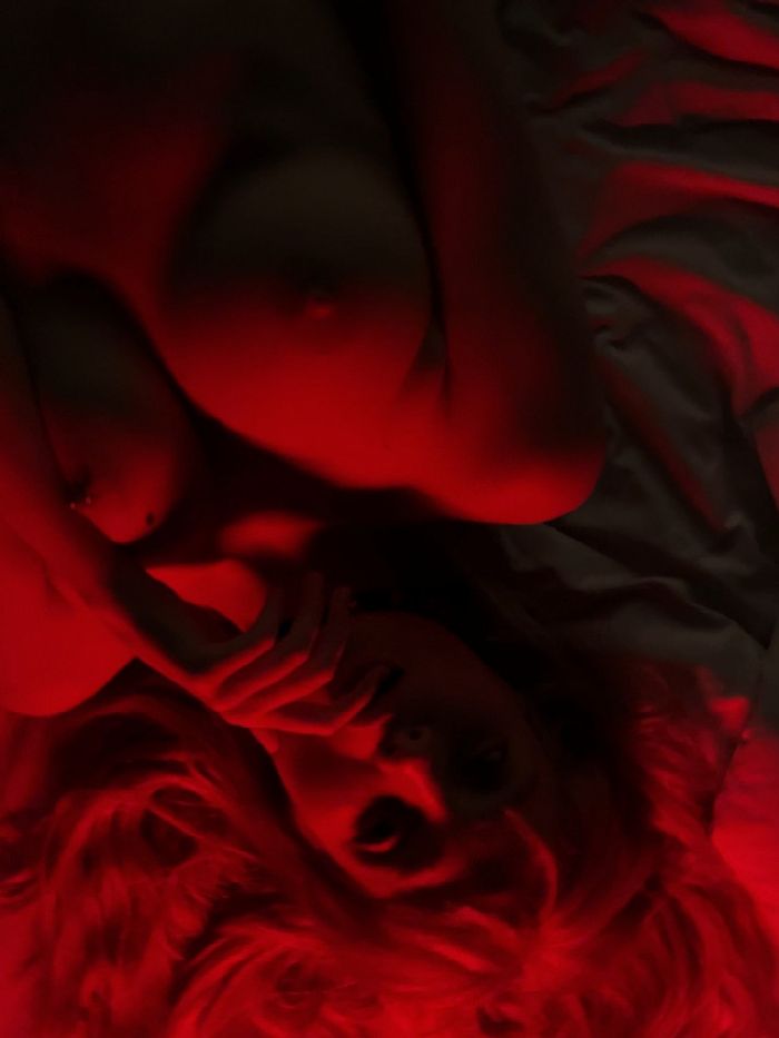 beautiful model lying on her back without bra in dim red light