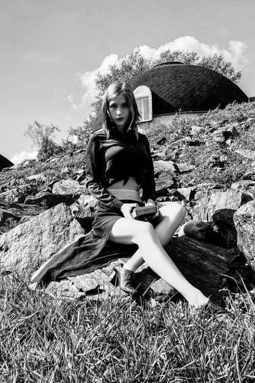 JessWoodstock sitting on a rock outdoors wearing a long skirt