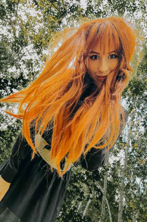 JessWoodstock wearing a hippie style red wig, smiling into the camera 