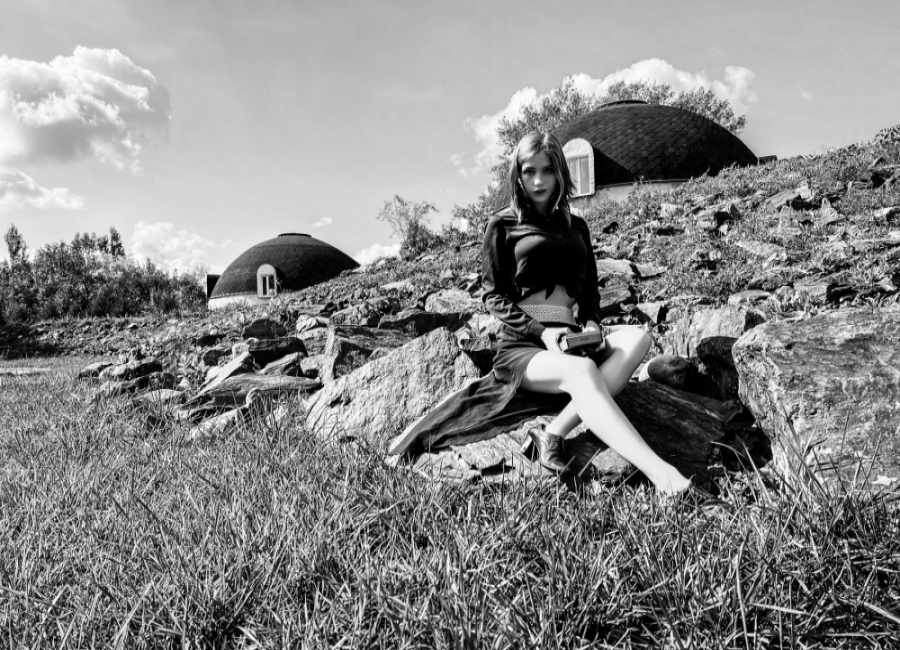 JessWoodstock sitting on a rock outdoors wearing a long skirt